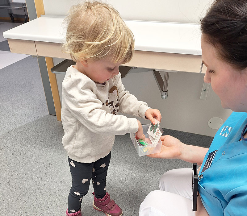 Liten flicka väljer leksak hos tandläkaren ur en liten burk.