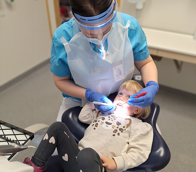 Tandläkare räknar och känner på 3-årings tänder.