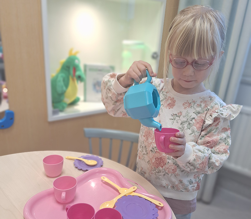 Flicka leker med köksleksaker i ett väntrum.