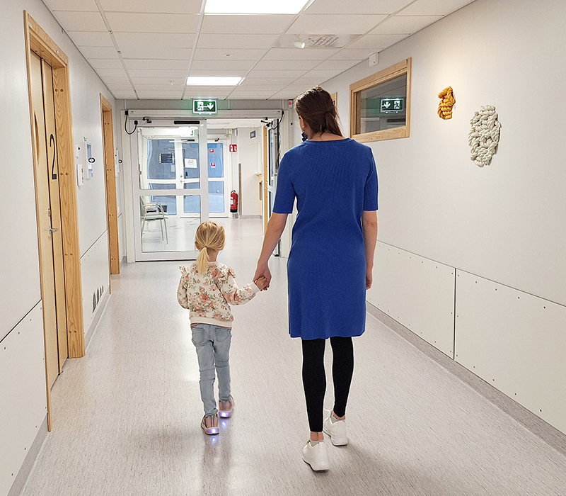 Flicka håller en vuxen i handen och går ut från tandläkarmottagningen.