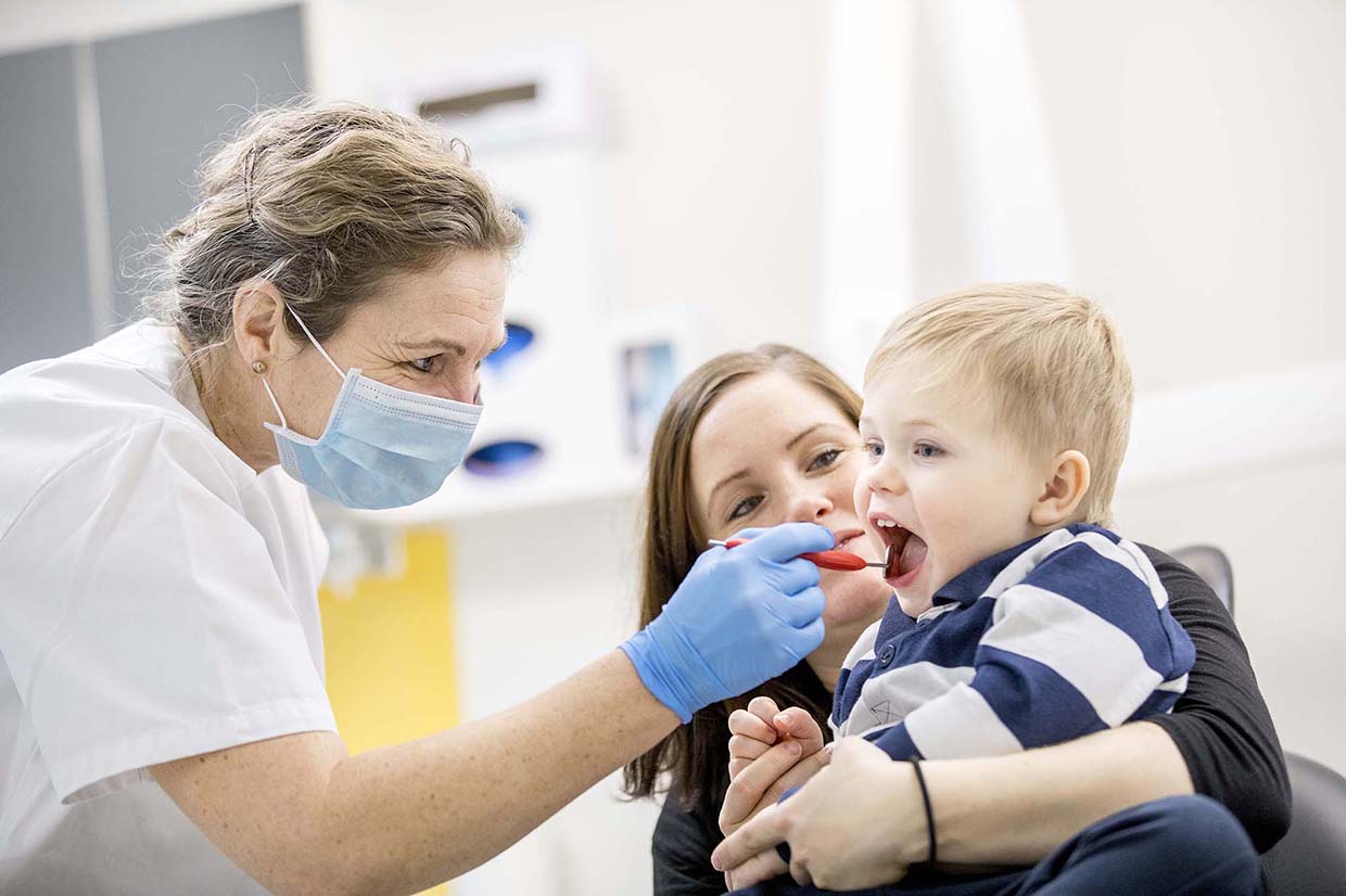 Tandhygienisten tittar i barnets mun med en munspegel