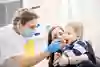 Tandhygienisten tittar i barnets mun med en munspegel