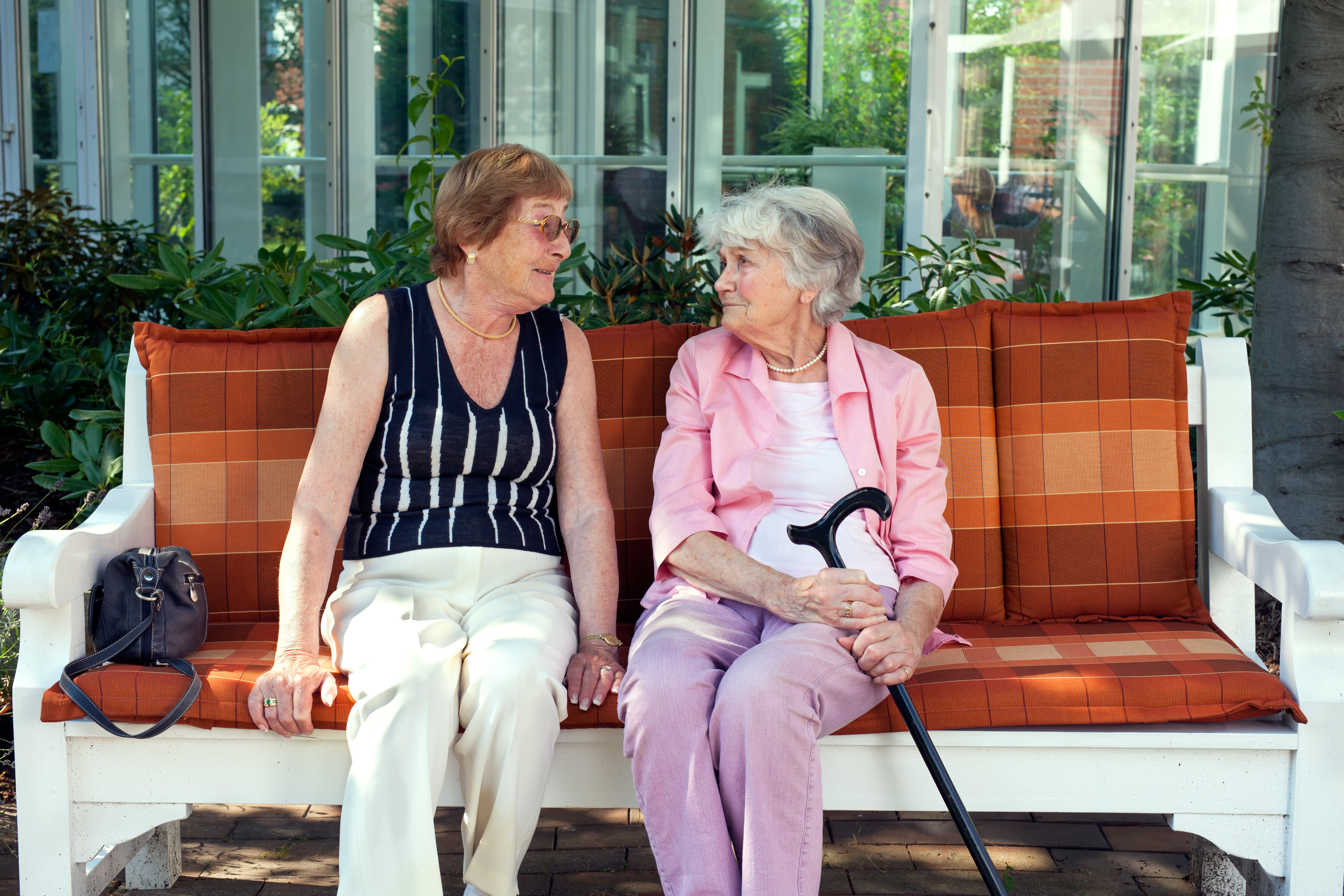 två äldre kvinnor sitter tillsammans på en bänk