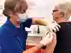 sjuksköterska med munskydd vaccinerar en kvinna