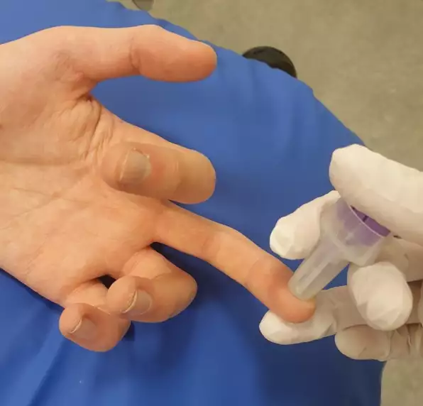Sköterska sticker med en nål i fingret