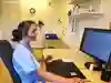 Sjuksköterska med hörlurar sitter framför en dataskärm