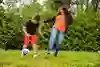 En pojke och en kvinna som spelar fotboll i gräset
