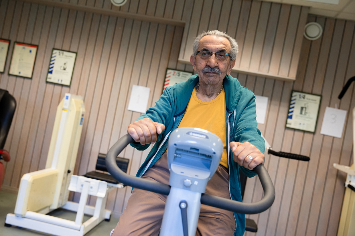 Äldre man i gymmet på en träningscykel.