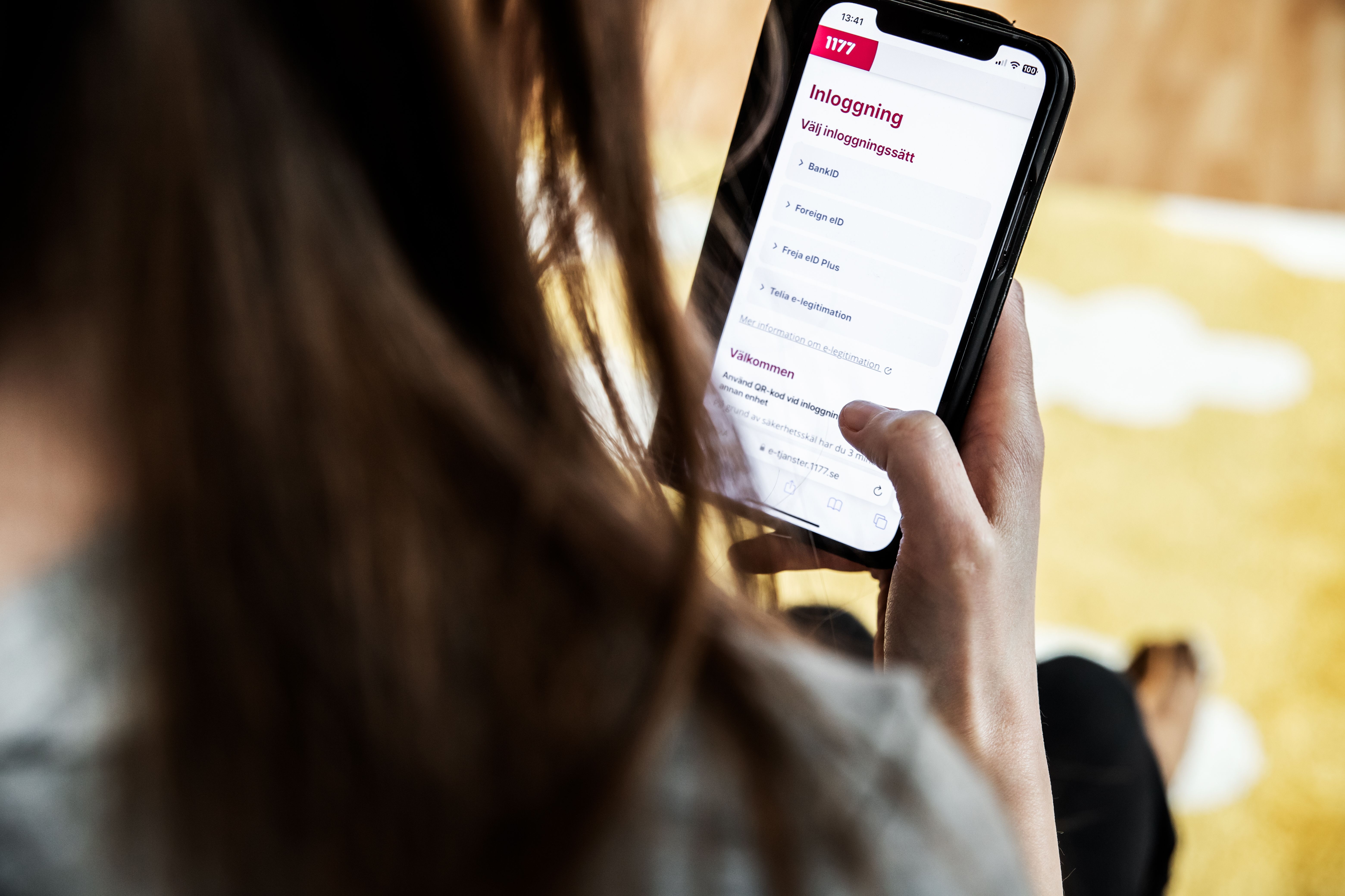 Kvinna som sitter med mobiltelefon i inloggat läge för e-tjänster