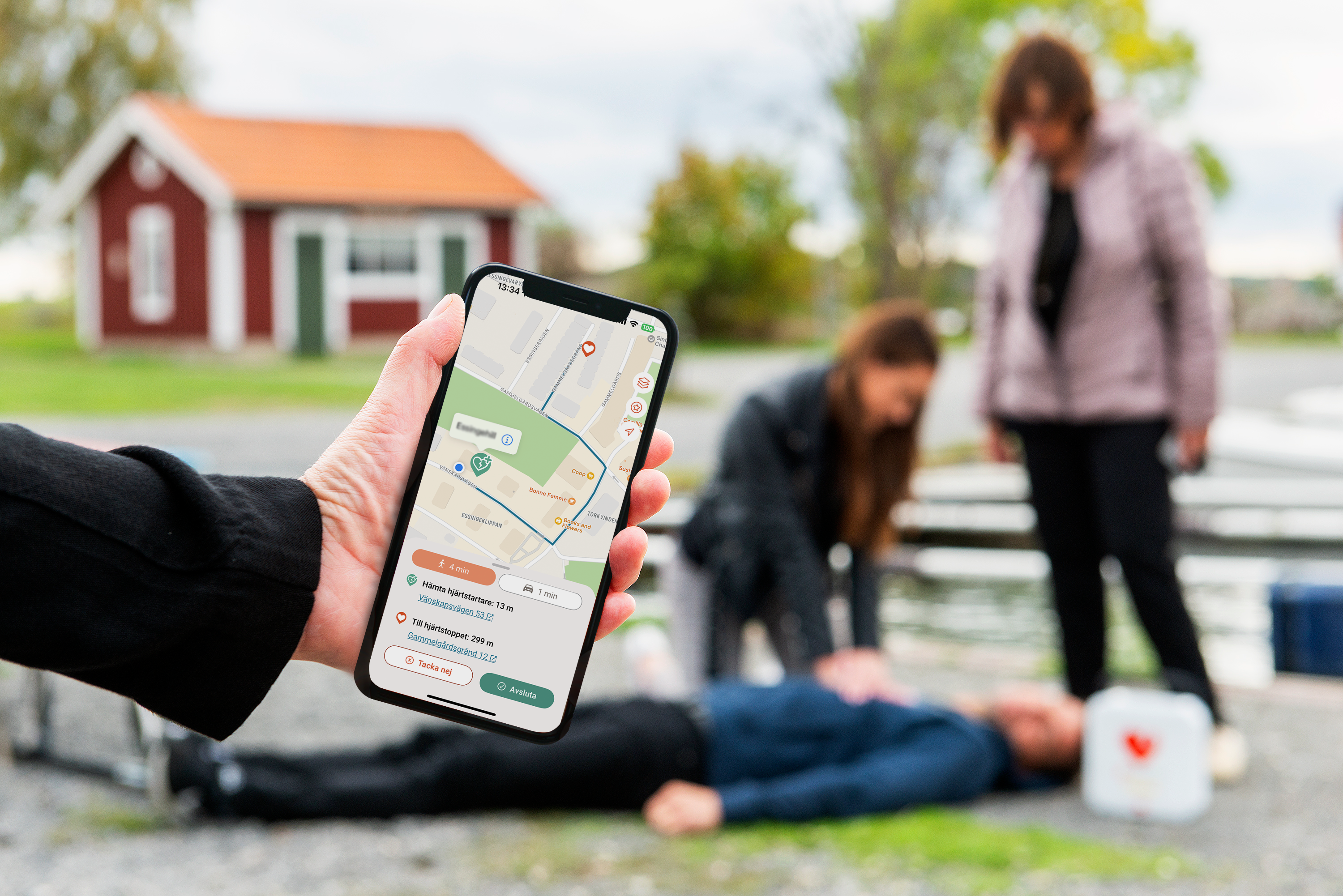 Appen i förgrunden som sms-livräddare har och sedan två personer med någon på marken som behöver HLR.