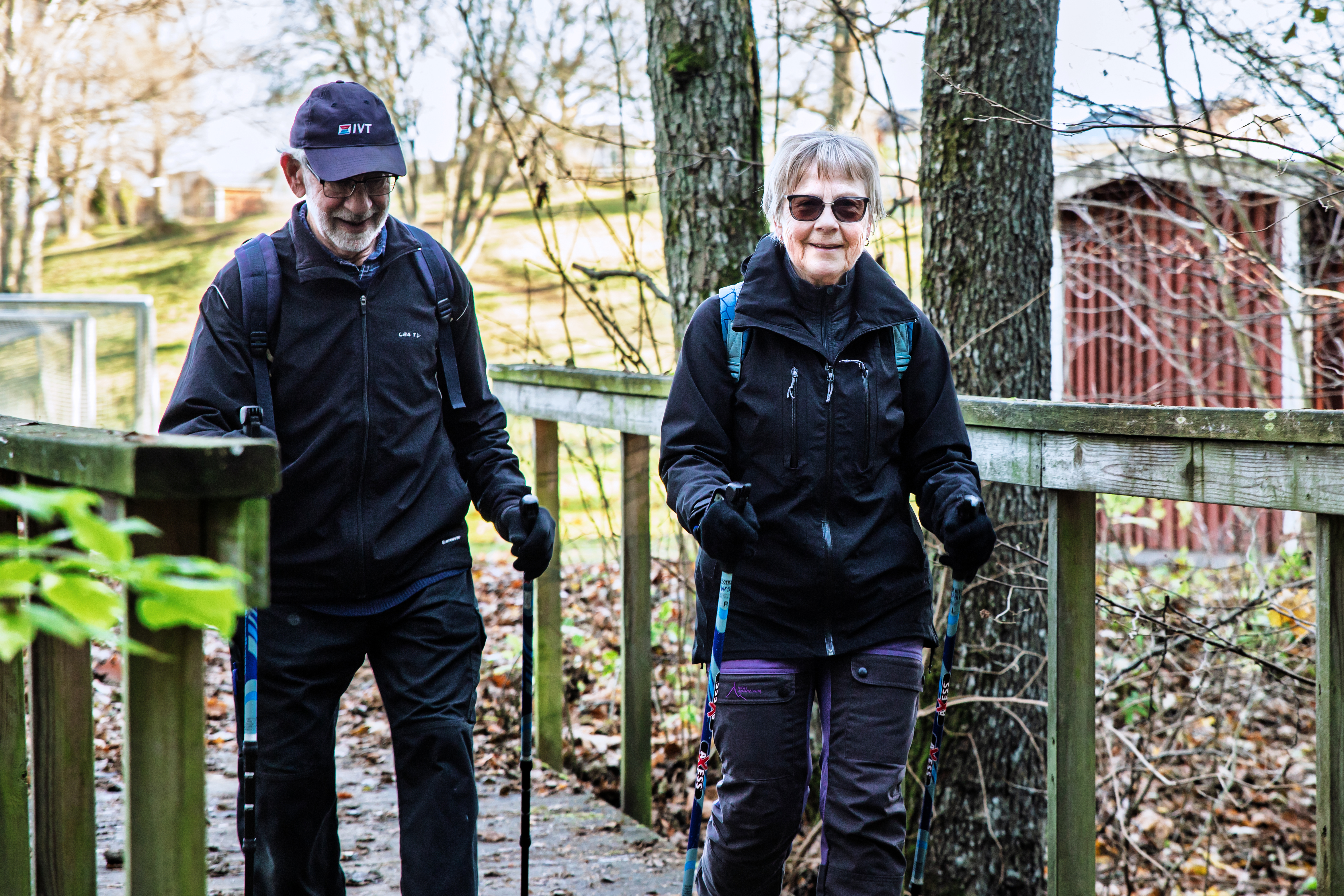 Två äldre personer som är ute och går stavgång tillsammans.