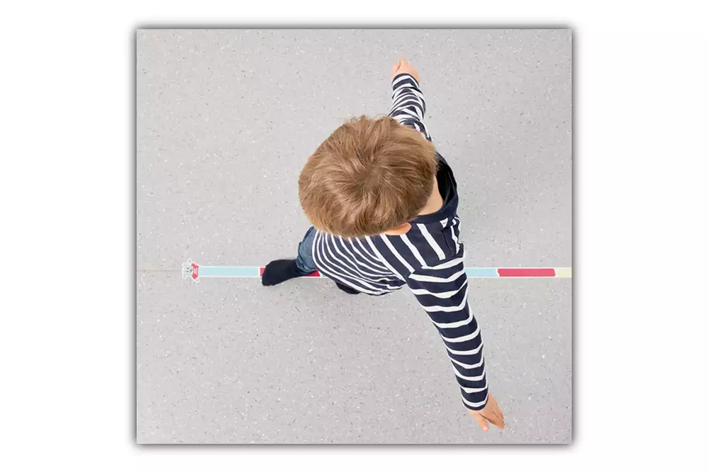 Barn som går på en balanslinje på ett golv i barnhälsovården.
