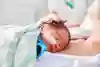 Bäbis med sond ligger med huvudet tyckt mot förälders bröst