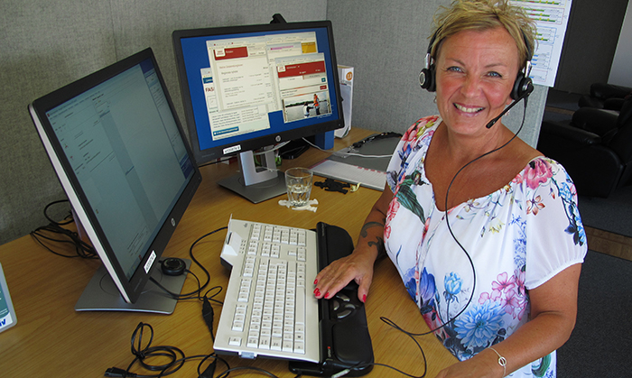 Catharina sitter vid skrivbordet på sin arbetsplats, 1177 Vårdguiden på telefon
