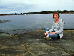 Dansterapeut Marit Mörk sitter på en klippa vid vattnet