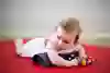 Ett litet barn ligger på mage med en rullad handuk under bröstet
