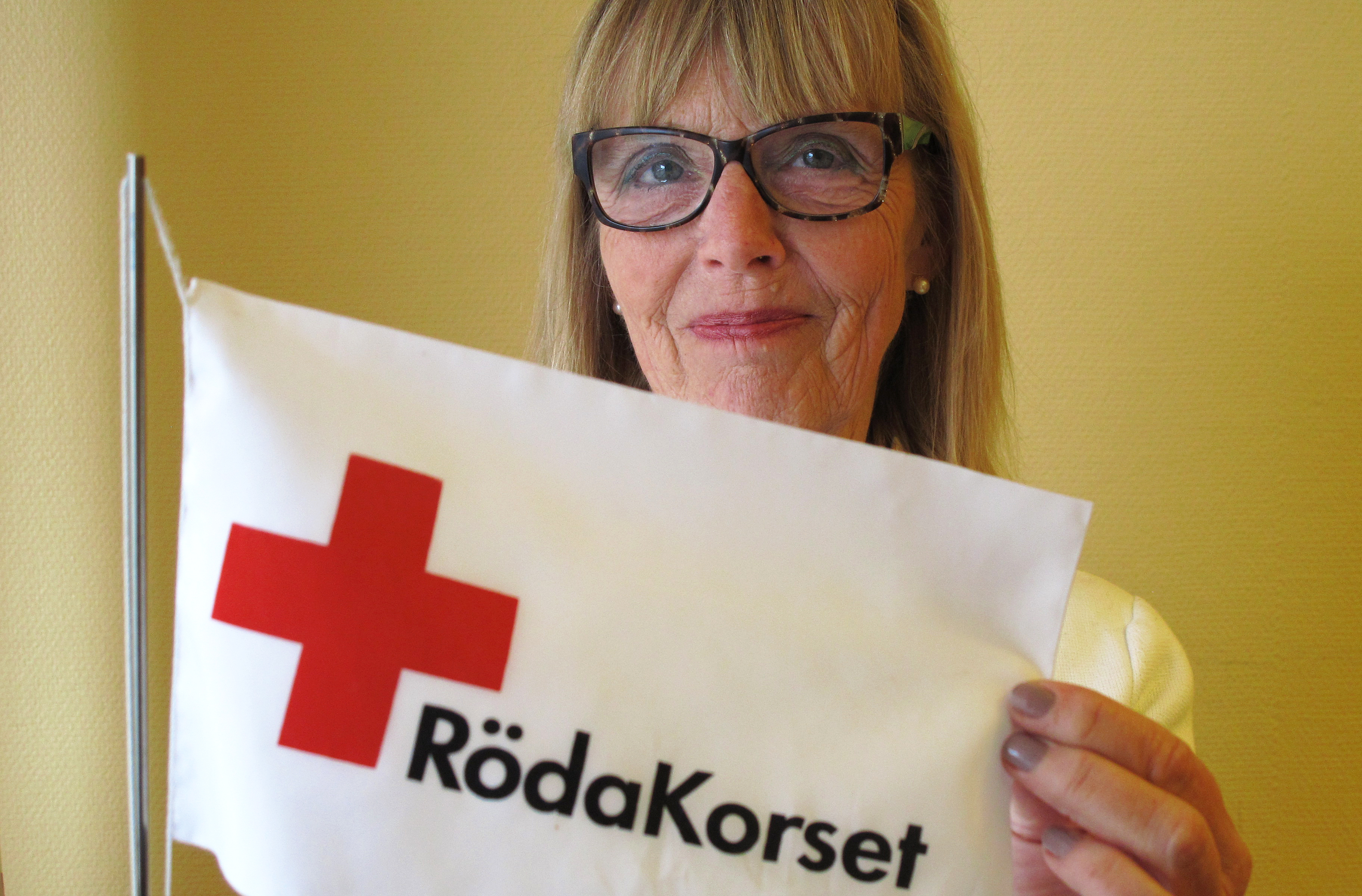Christina Hammargren håller upp en Röda Korset-flagga