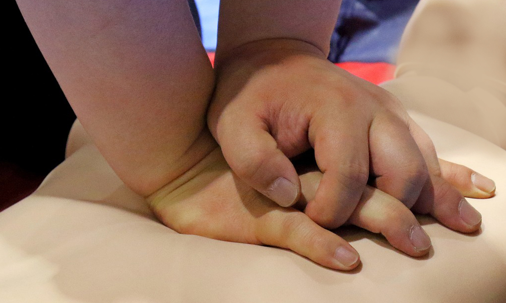 Två händer på en bröstkorg. De gör hjärtkompressioner.