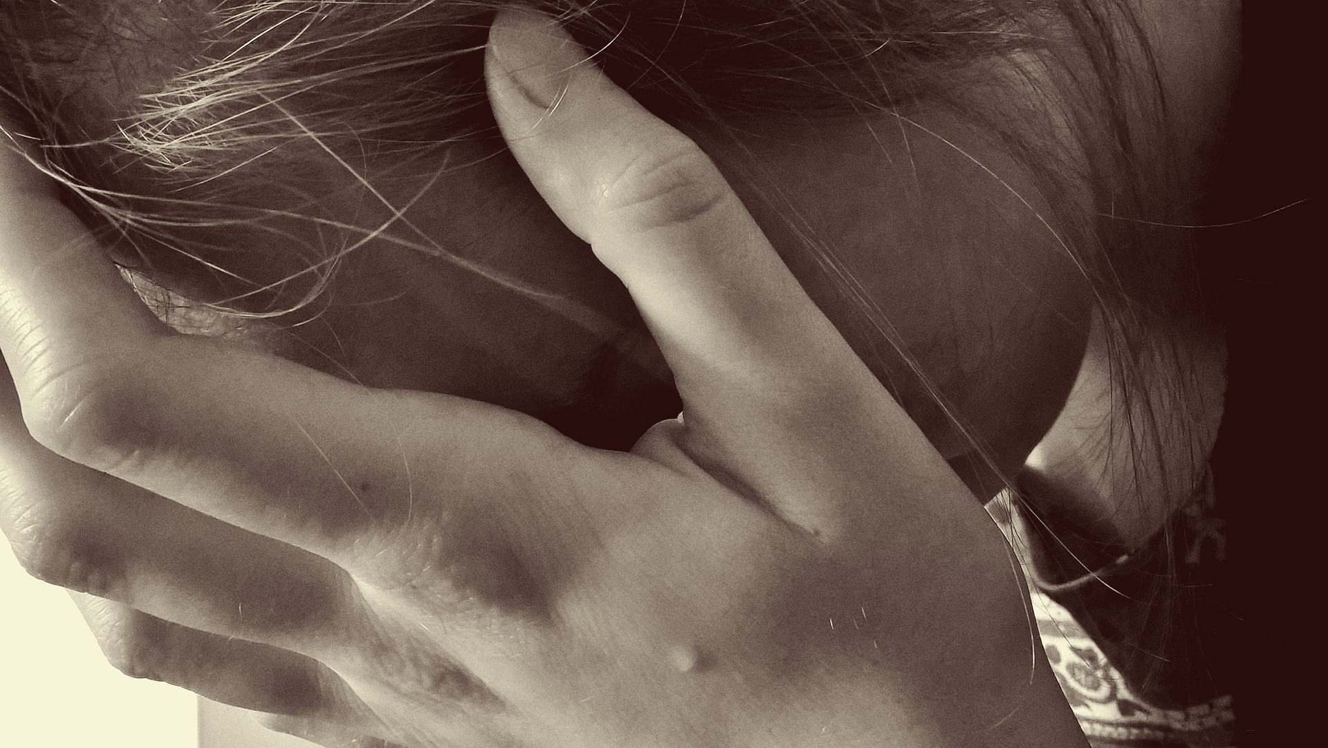 Kvinna döljer sitt ledsna ansikte i handen