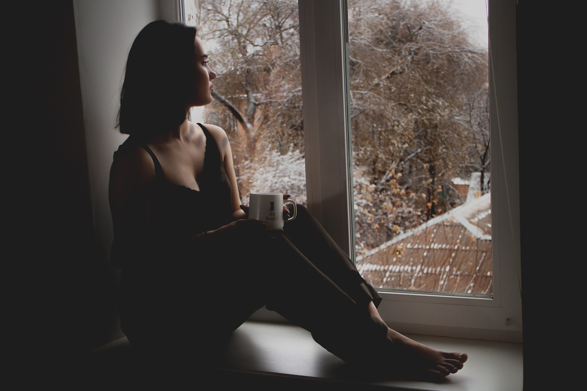 Ung kvinna sitter och tittar ut genom fönster