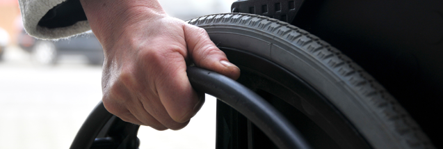 Hand rullar hjulet på en rullstol